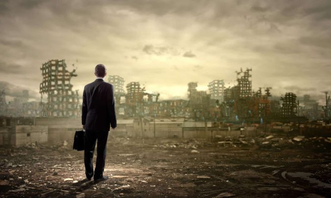 A person in a suit, briefcase in hand, stands on a desolate landscape like a career in ruins. They face a skyline of partially constructed, abandoned buildings beneath the ominous, cloudy sky.