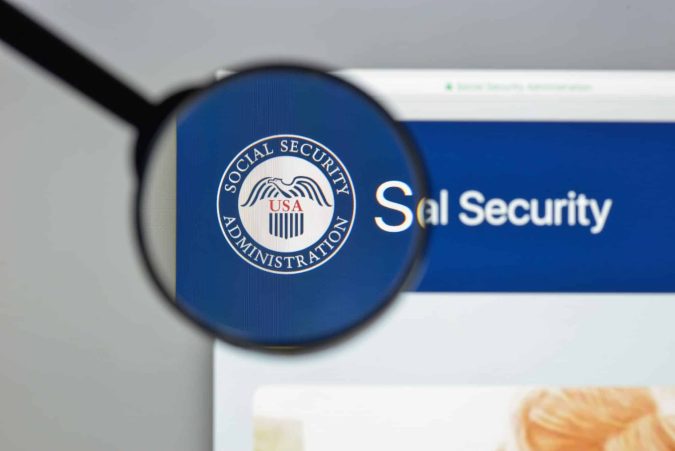 A magnifying glass focuses on the Social Security Administration logo on a computer screen, highlighting important details about qualifying for disability benefits.