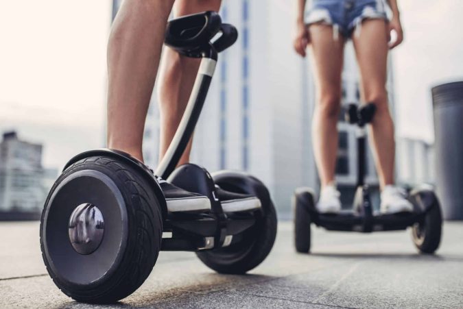 Two teenagers using electric scooters in the streets of Lansing
