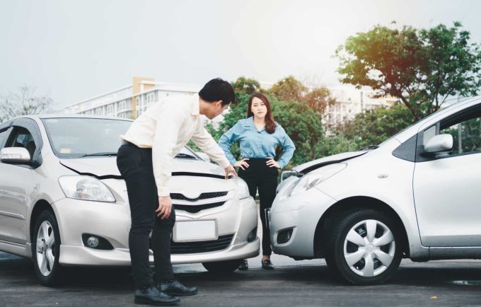 What Is Needed To Prove Fault in an Auto Accident Two people examine the damage between two cars involved in a minor auto accident on a street, attempting to prove fault.