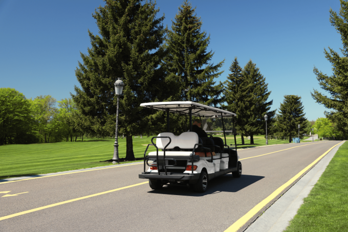 Can I Drive My ATV or Golf Cart on Main Michigan Streets A person leisurely drives a white golf cart along the picturesque Michigan streets, lined with trees and basking under a clear blue sky.