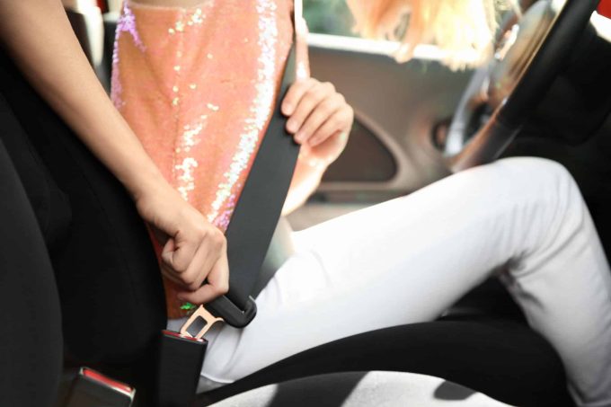 seat belt injury heal A person in a pink sequin top carefully fastens a seatbelt while sitting in a car, mindful of the potential for seat belt injury.