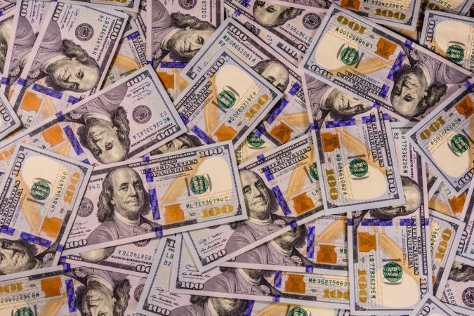 A scattered pile of U.S. one hundred dollar bills, hinting at the potential worth of a personal injury case in Lansing, displays various angles and overlaps elegantly.