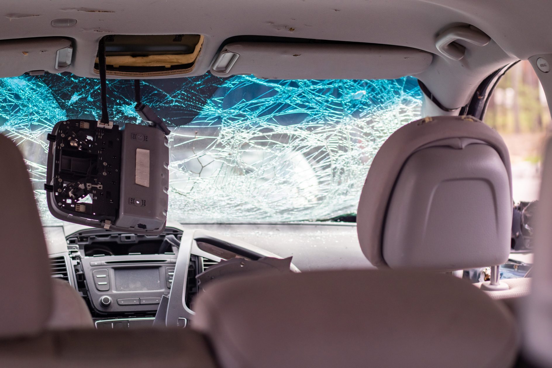 The interior of the car reveals a shattered windshield and a detached rearview mirror hanging down, a vivid reminder of why uninsured motorist coverage is essential in places like Lansing.