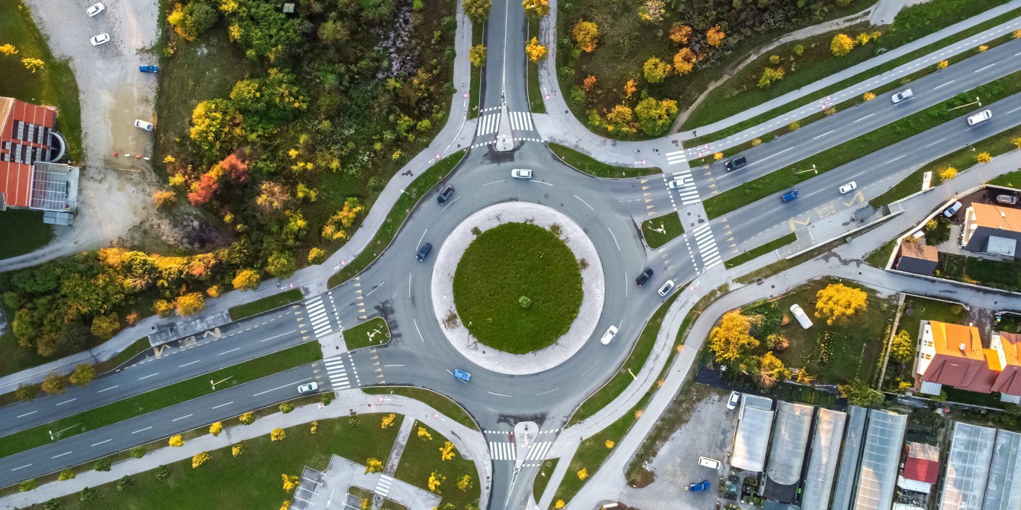 Lansing roundabout accidents Aerial view of a large roundabout with multiple roads converging in Lansing, highlighting how Lansing roundabouts manage traffic dangers amid green areas, cars, and nearby buildings while promoting driving safety.