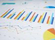 A close-up of printed charts showing colorful bar graphs, line graphs, and pie charts with monthly data on white paper.