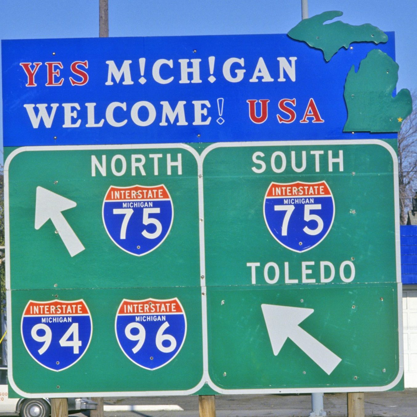 A large roadside sign in Michigan directs drivers to Interstates 75 North and South, 94, and 96, with an additional sign pointing south toward Toledo.