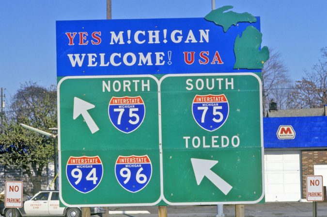 A large roadside sign in Michigan directs drivers to Interstates 75 North and South, 94, and 96, with an additional sign pointing south toward Toledo.