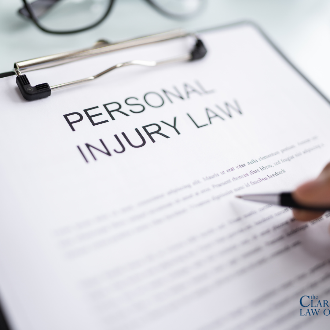 A clipboard holds a document titled “Personal Injury Law” with a hand holding a pen hovering over the paper; The Clark Law Office logo appears in the bottom right corner. A clipboard holds a document titled "Personal Injury Law" with a hand holding a pen hovering over the paper; The Clark Law Office logo appears in the bottom right corner.