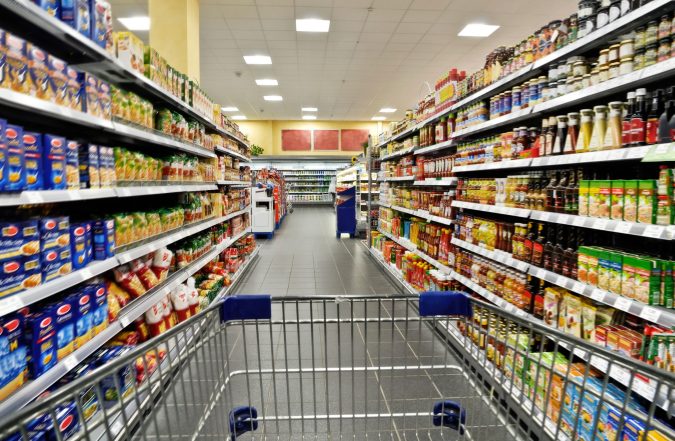 Meijer or Walmart Injury A shopping cart in a grocery store aisle, surrounded by shelves stocked with various food products and condiments.