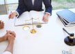 Two people sit across from a lawyer at a desk with legal books, scales of justice, and a gavel. The Clark Law Office logo is visible in the corner.